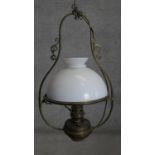 An Art Nouveau style scrolling design brass ceiling oil lamp with milk glass shade. H.80 x D.40cm