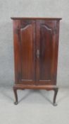 A C.1900 mahogany music cabinet with arched fielded panel doors on cabriole supports. H.100 W.53 D.