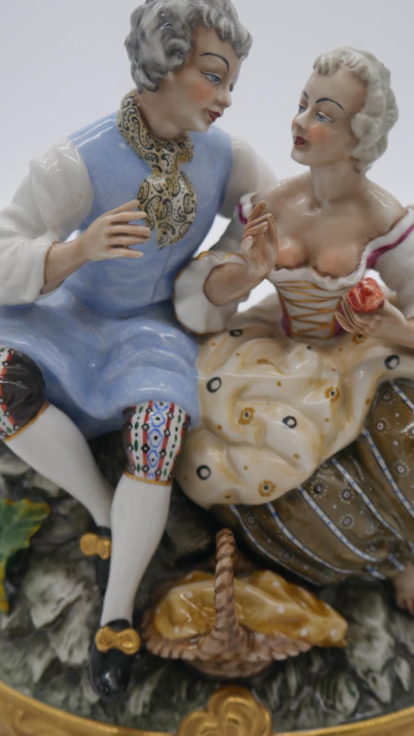A hand painted porcelain figure group of a pair of lovers seated on a rocky outcrop with picnic - Image 2 of 7