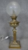 A converted Victorian brass oil lamp with fristed globe shade. The lamp has a fluted column design