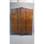 A mid century burr walnut wardrobe fitted with slides and drawers and standing on squat cabriole