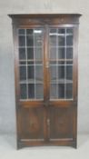 A mid century oak library bookcase with leaded glazed panel doors above cupboards. H.200 W.90 D.38cm