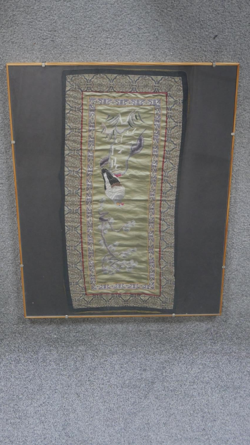 A framed and glazed Chinese silk embroidery of a bird of prey in a tree with silk ribbon border. H.