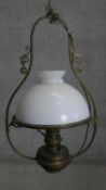 An Art Nouveau style scrolling design brass ceiling oil lamp with milk glass shade. H.80 x D.40cm