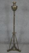 A Victorian brass floor standing oil lamp with tripod base and stylised foliate design. H.140cm
