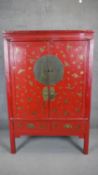 A 19th century Chinese red lacquered marriage cabinet with all over hand gilded decoration. H.175
