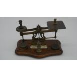 A set of early 20th century brass postage scales on shaped mahogany base, bearing ivorine central