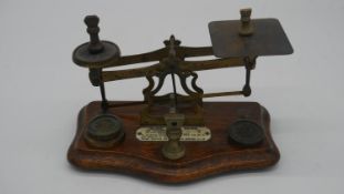 A set of early 20th century brass postage scales on shaped mahogany base, bearing ivorine central