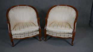 A pair of Louis XV style tub armchairs in striped upholstery on carved cabriole supports.