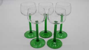 Five vintage green stemmed wine glasses.