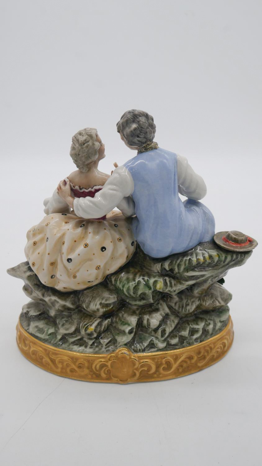 A hand painted porcelain figure group of a pair of lovers seated on a rocky outcrop with picnic - Image 6 of 7