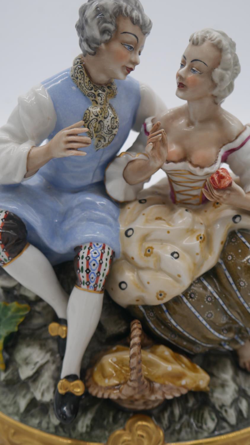 A hand painted porcelain figure group of a pair of lovers seated on a rocky outcrop with picnic - Image 5 of 7