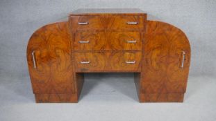 An Art Deco burr walnut sideboard with central drawers flanked by arched cupboards on plinth base.