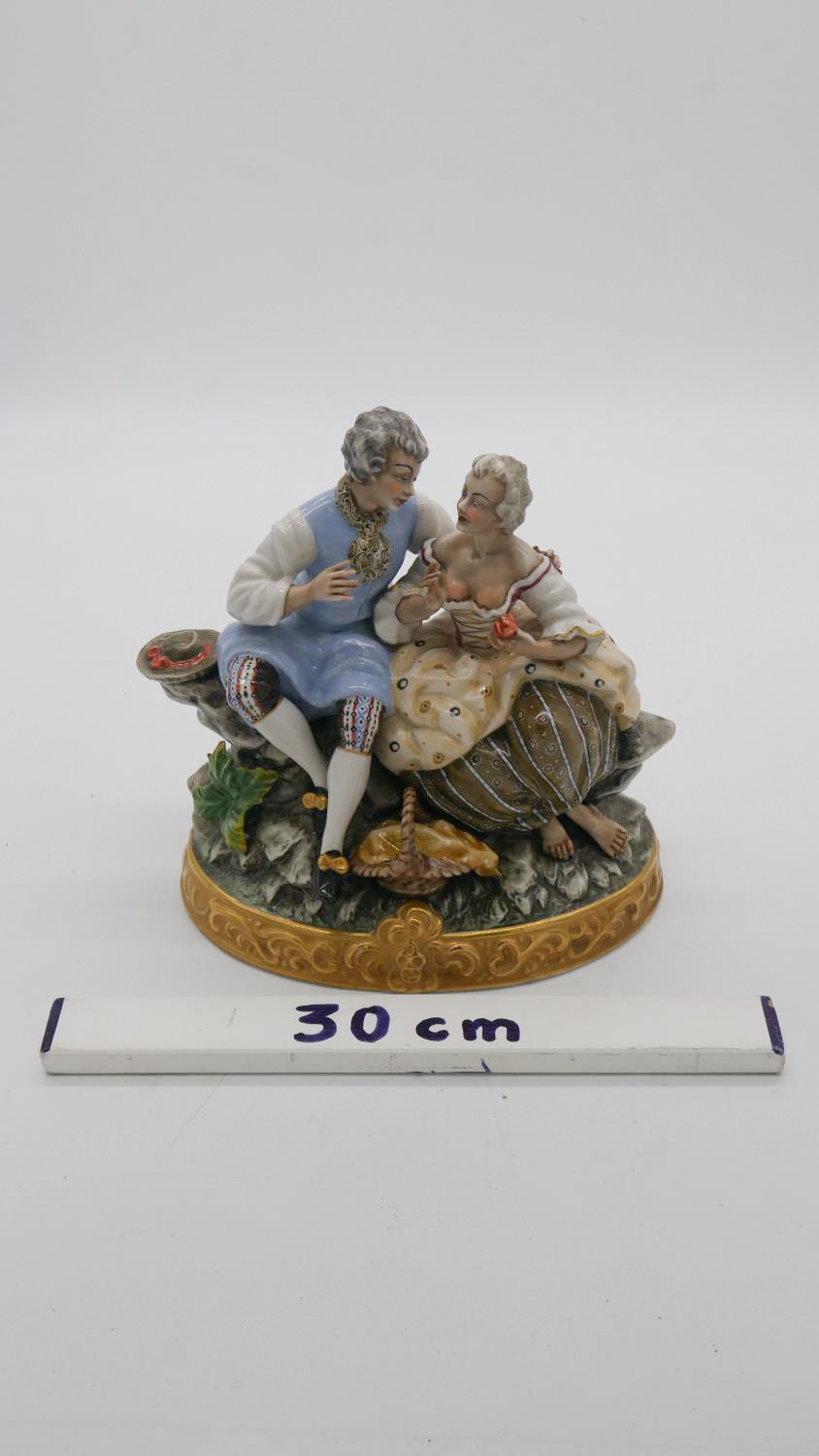 A hand painted porcelain figure group of a pair of lovers seated on a rocky outcrop with picnic - Image 3 of 7