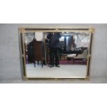 A contemporary gilt and ebonised wall mirror with bevelled plate. H.110 W.137cm