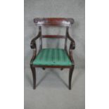 A Regency mahogany armchair with carved backrail and drop in seat on sabre supports.