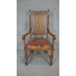 A mid century carved oak Carolean style armchair with caned back and leather seat on barleytwist
