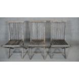 A set of three weathered teak folding slatted garden chairs.