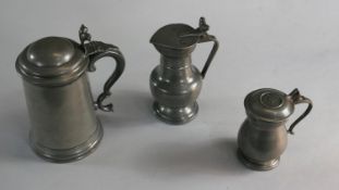 Three 18th and 19th century pewter lidded flagons. One with acorn motifs to the handles and makers