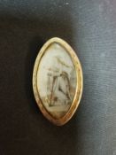 A Georgian yellow metal mourning brooch of oval form decorated with a lady leaning on an anchor on a
