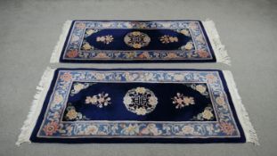 A pair of Chinese rugs with central medallion on a deep blue ground in floral borders. L. 144 W. 70