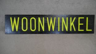 A very large light up sign with neon yellow lettering 'WOONWINKEL'. H.44 W.200cm