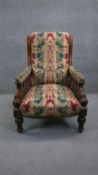 A Victorian carved mahogany framed armchair in floral upholstery on turned tapering supports.