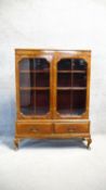 A mid century walnut and crossbanded bookcase fitted with base drawers on cabriole supports. H. 12