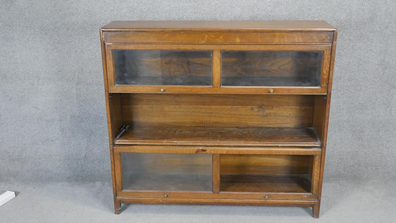 A mid century oak sectional bookcase with glazed sliding doors. Each part breaks down and is flat