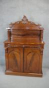 A Victorian flame mahogany chiffonier with carved superstructure above arched panel doors on