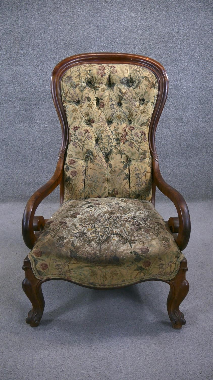 A 19th century mahogany framed spoon back armchair in deep buttoned upholstery on carved cabriole
