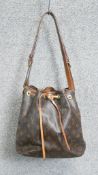 A vintage Louis Vuitton draw string bucket bag with monogrammed design, tan leather carrying strap
