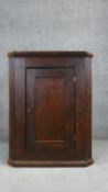 A Georgian country elm hanging corner cabinet. H. 99 W. 84 D.43