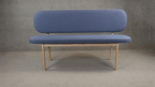 A contemporary limed hardwood bench with upholstered back and seat. H. 90 W. 150 D.45