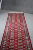 Red ground hand made woollen Bokhara runner. L.470 W.80cm