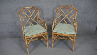 A pair of vintage bamboo conservatory armchairs with squab cushions on woven seats.