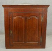 A Georgian oak hanging corner cabinet with twin arched fielded panel doors enclosing shelves. H.