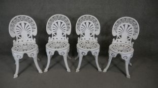 A set of four white painted wrought metal garden chairs with greek key and palmette decorated backs.