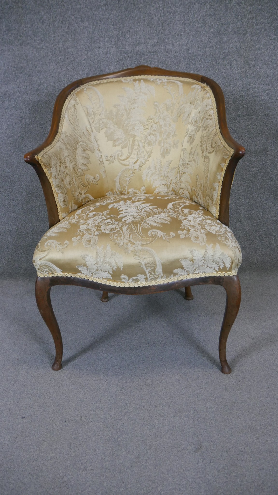 A mid century Continental style mahogany framed armchair in floral damask upholstery raised on