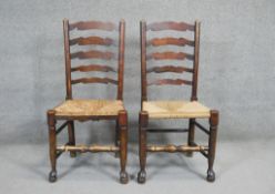 A pair of oak Lancashire style ladder back dining chairs with woven rush seats.