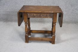 A small mid century oak Jacobean style twin drop flap occasional table with carved frieze on