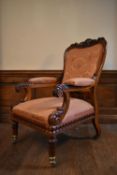 A 19th century carved rosewood library armchair in buttoned floral damask upholstery on acanthus