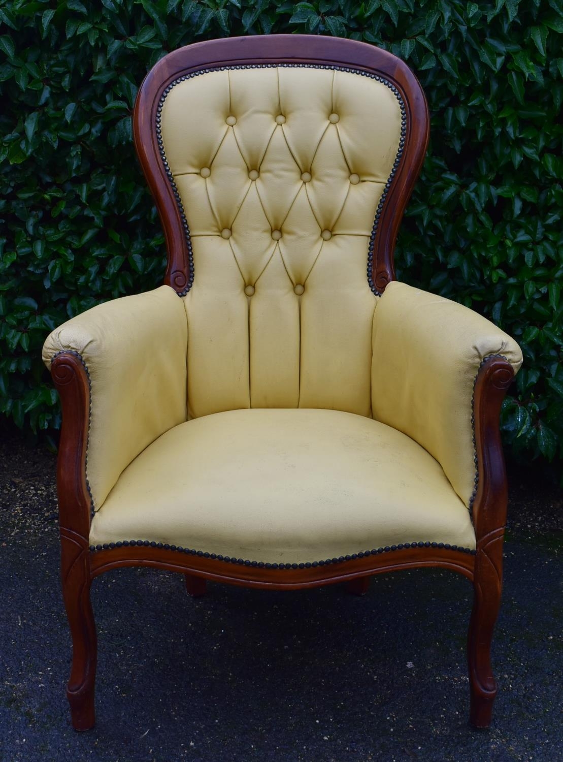 A 19th century style mahogany framed armchair in deep buttoned faux leather upholstery. H.102 W.70