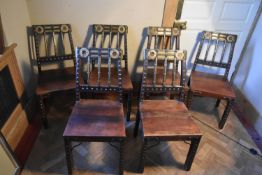 A set of six Eastern iron bound hard wood dining chairs with brass mounts and panel seats on