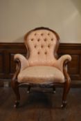 A 19th century carved walnut armchair in deep buttoned floral damask upholstery on cabriole