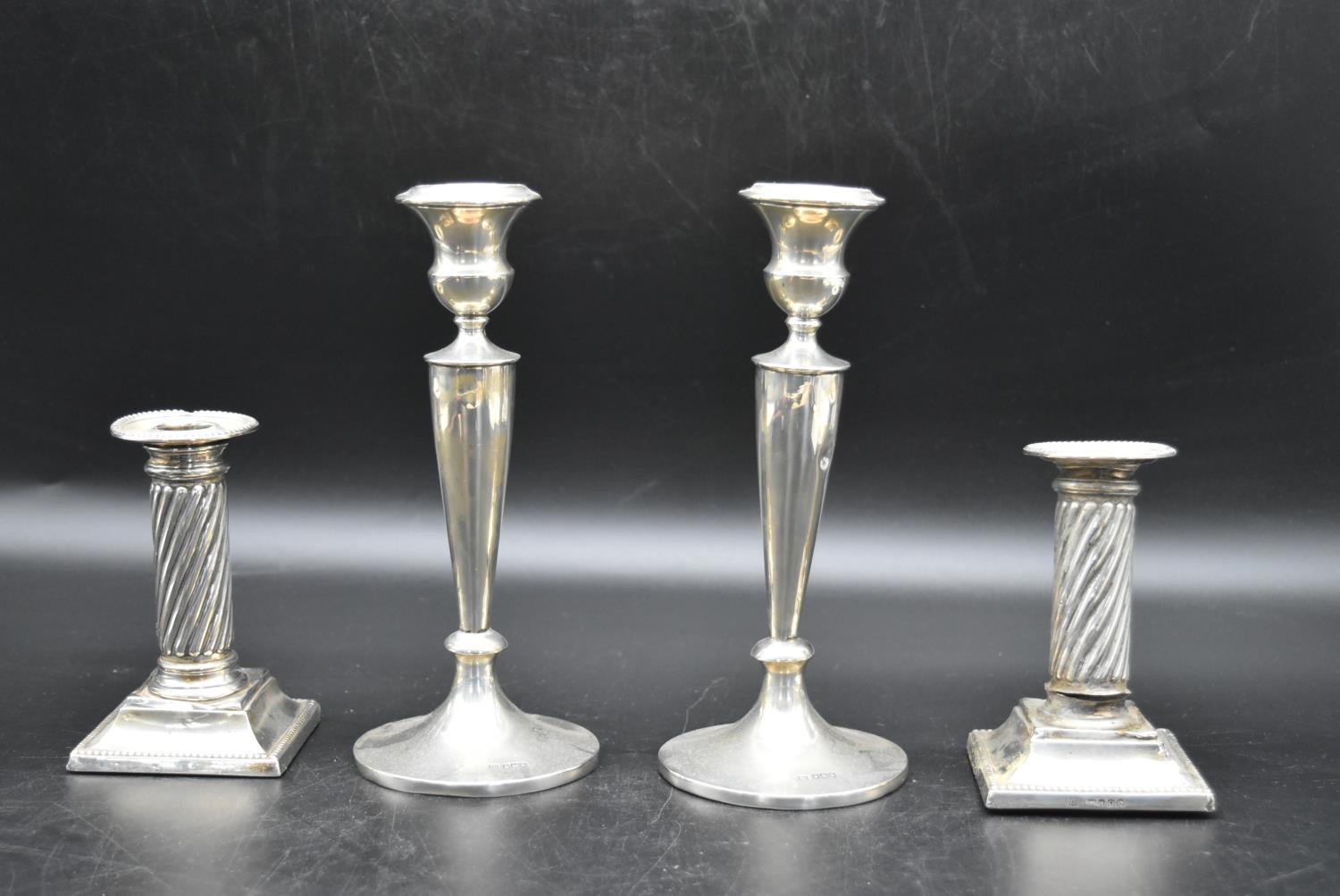 A pair of silver candlesticks with a twisted style to the column and beading decoration to the base,