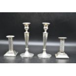 A pair of silver candlesticks with a twisted style to the column and beading decoration to the base,