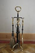A contemporary wrought iron fire stand with four utensils with brass detail to the handles. To