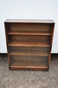 A vintage bookcase with open shelves above sliding glass doors