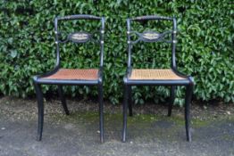 A pair of Regency ebonised dining chairs with rope twist backs above caned seats on sabre